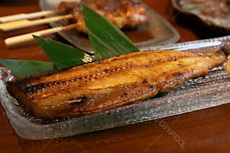 Grilled fish fillet lemon wedge grated radish green leaf on wooden table, Japanese style