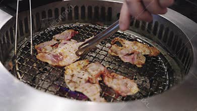 Delicious slices of marinated meat grilling on metal mesh over hot coals in a traditional BBQ restaurant.