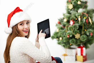 Woman sitting with tablet PC over Christmas tree