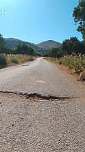 Rural asphalt road with cracks leading to mountains