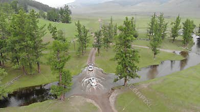 Two white SUVs cross a river on a dirt road through Siberian taiga meadow terrain, vehicle, crossing, convoy, off road