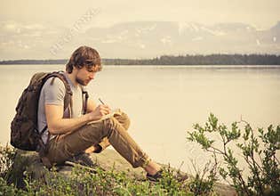 Young Man Traveler with backpack reading book