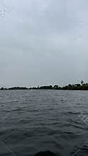 Wide lake view with rippling dark water, low tree lined shore, distant