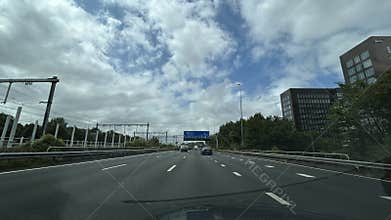Modern highway through Amsterdam business district with moving traffic, rail