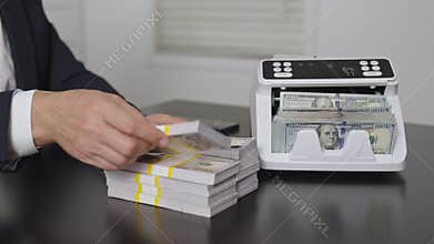 Male hand with counting money machine in office. Handling money. Businessman counting dollars close-up. Banker counting money