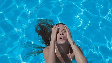 girl in a white bikini swimming in the pool