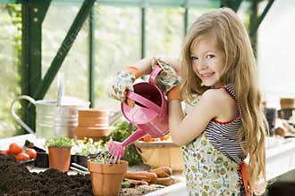 Young girl watering plants in greenhouse
