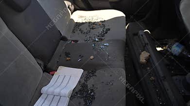 Broken car window with glass shards inside vehicle after theft