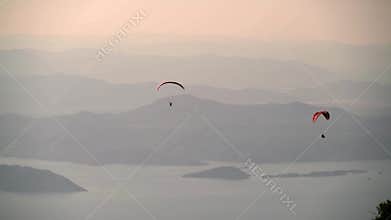 Paragliders glide above forested mountains and sea near Fethiye and Babadag in Turkiye, paragliding, coastal flight, mediterranean