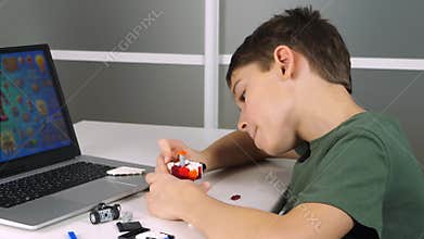 AI assistant kids helps child assemble construction set. Child builds model with AI assistant while looking at monitor screen
