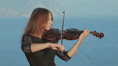 Beautiful violinist in tracery dress plays on a