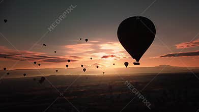 Serene scene of single hot air balloon during sunrise with distant convoy and soothing sunlight