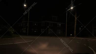 Quiet nighttime city road with forward driving viewpoint, streetlights, parked