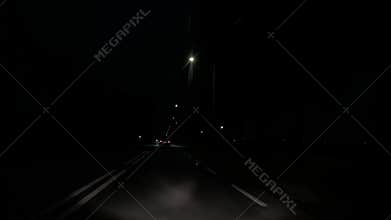 Dark nighttime highway with distant truck headlights and sparse streetlights
