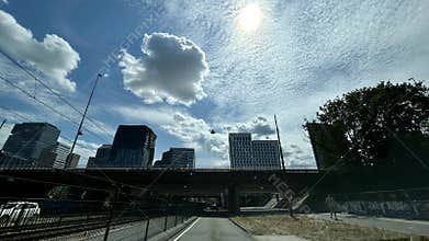 Bright urban skyline beneath dramatic cloud filled sky with sun glare over