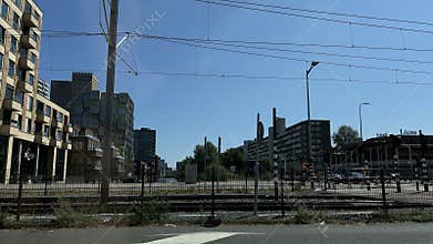 Urban tram corridor beside modern apartment towers, overhead power lines, rail