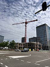 Tower crane above modern office construction beside wide city intersection