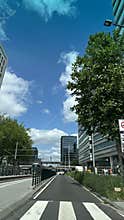 Modern office building and tram at urban street with blue sky and