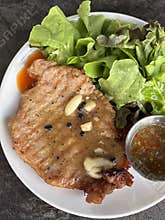 Grilled pork chop with garlic and peppercorn served with green leaf salad and dipping sauce, savory and fresh