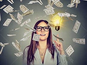 Happy woman in glasses has a successful idea under money rain