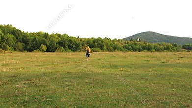 Little girl runs away. Girl runs away in front of camera. Girl running on the field. Girl with long curly hair. View from the back