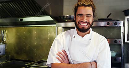 Happy chef with arms crossed standing in kitchen