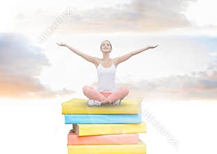 Girl meditating on Books stacked by brick wall