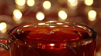 Sugar drops into hot black tea in closeups. Slow motion