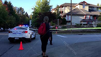 Woman asking fire situation to police between police caution line in residential neighborhood street blocking traffic