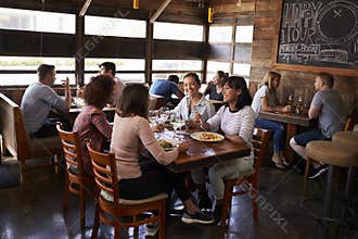 Four female friends at lunch in busy restaurant, full length