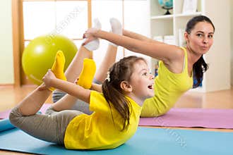 Mother and kid in the gym centre doing stretching fitness exercise. Yoga