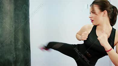 Beautiful brunette boxing pear, Beautiful Kickboxing woman training punching bag in fitness studio fierce strength fit