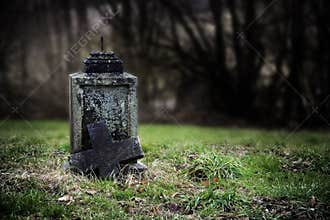 Broken stone cross, weathered gravestone on an old abandoned cemetery, concept for transience or gloomy halloween background with