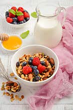 Homemade granola with fresh berries on white wooden background
