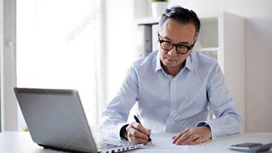 Businessman with laptop and papers at office