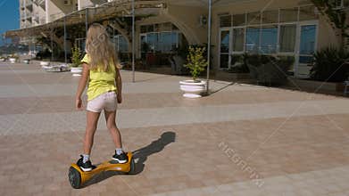 Preschooler girl riding on the hoverboard in the park