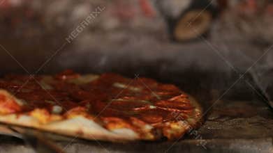 Pizza rotating and cooking in brick oven