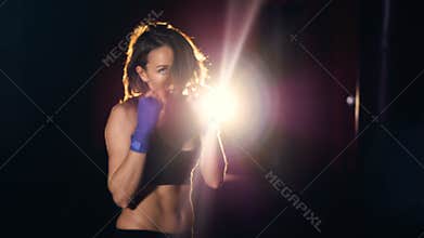 Confident young woman in boxing gloves boxing looking at camera.