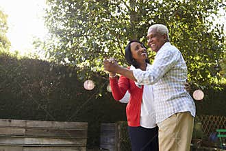 Senior black couple dancing in their back garden