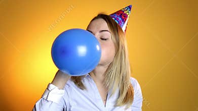 Girl inflating a balloon on a yellow background