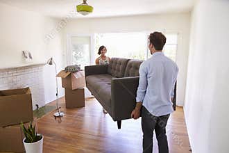 Couple Carrying Sofa Into New Home On Moving Day