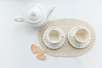Tea for two. Two white cups of tea with two hearts and kettle.