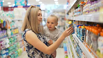Mum together with daughter look for child`s fruit puree and juices
