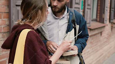 Young happy couple standing outside and reading the cards. Hipster man and woman playing the board game or quest.