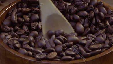 Coffee beans are mixed with a wooden spoon and are collected in a wooden spoon.