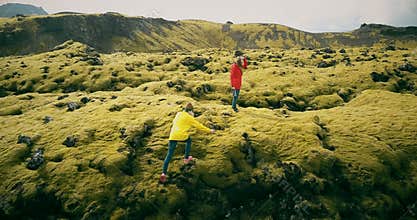 Aerial view of the two woman walking, hiking on the lava field in Iceland. Tourists falls down on the soft moss.