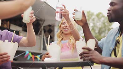 Friends clinking bottles of drinks at food truck