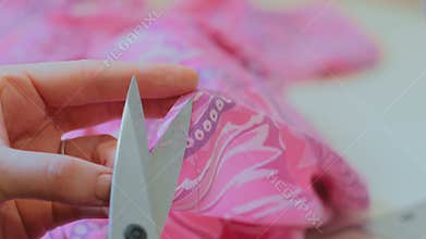 Professional dressmaker, tailor cutting a piece of cloth in her workshop