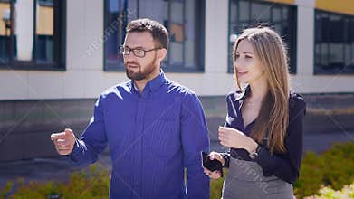 Business colleagues are walking in the office together after lunch break along building in the background. Two managers