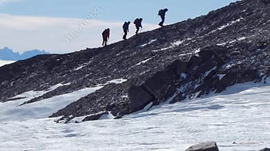 Climbers climb the mountain with snow field. Four climbers ascend the hill
